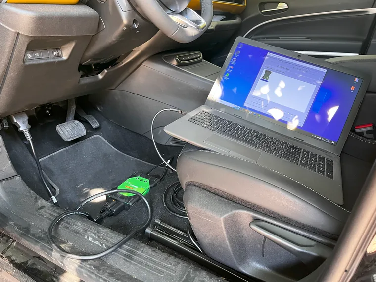 Modulo Crash Data Retrieval collegato alla presa diagnostica di un veicolo, con il portatile sul sedile che esegue il software di acquisizione
