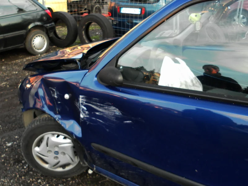 Utilitaria con la fiancata e il parafango deformati dopo un urto, airbag aperto visibile dal finestrino