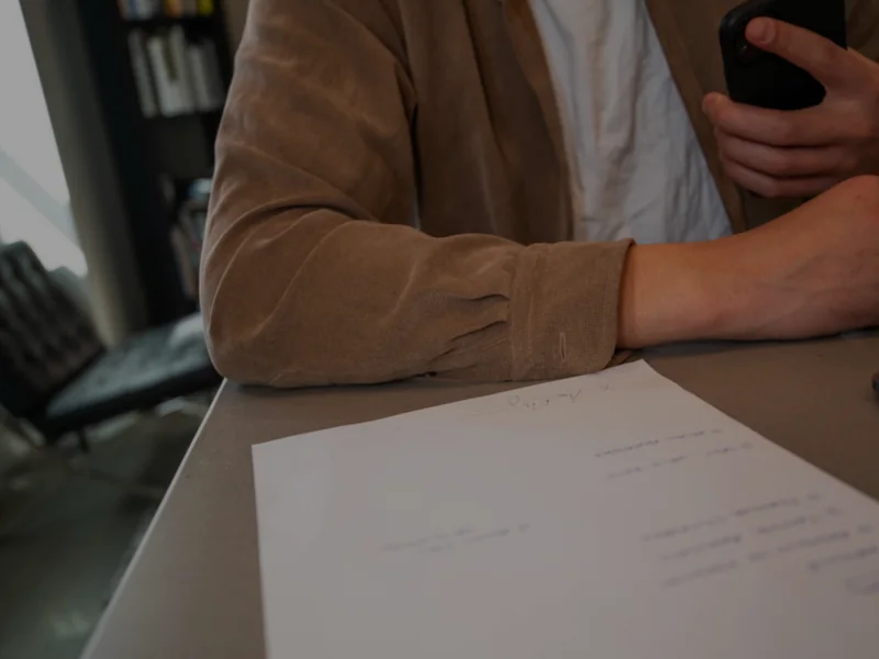 Mani appoggiate a una scrivania accanto a un documento firmato